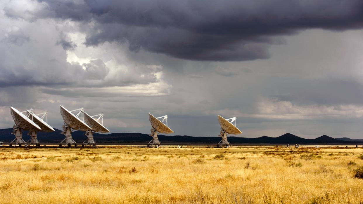  A series of large white radar dishes stand alone in the desert. 