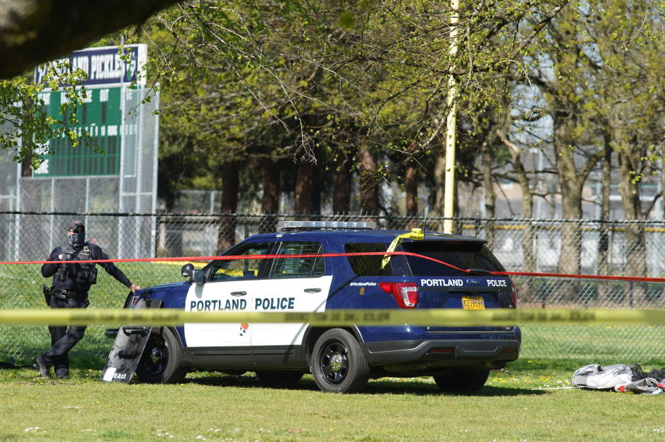 A Portland Police officer stand by following a police involved shooting of a man at Lents Park, Friday, April 16, 2021, in Portland, Ore. Police fatally shot a man in the city park Friday morning after responding to reports of a person with a gun, authorities said. (Beth Nakamura/The Oregonian/The Oregonian via AP)