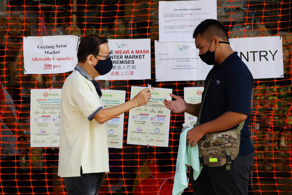 SINGAPORE - APRIL 23:  A man wearing protective mask shows his identification card before entering a wet market on April 23, 2020 in Singapore. The Singapore government further enhanced stringent measures by closing more workplaces and imposing entry restriction to popular places and will extend the partial lockdown until June 1 to bring down the coronavirus (COVID-19) cases within the community.  (Photo by Suhaimi Abdullah/Getty Images)