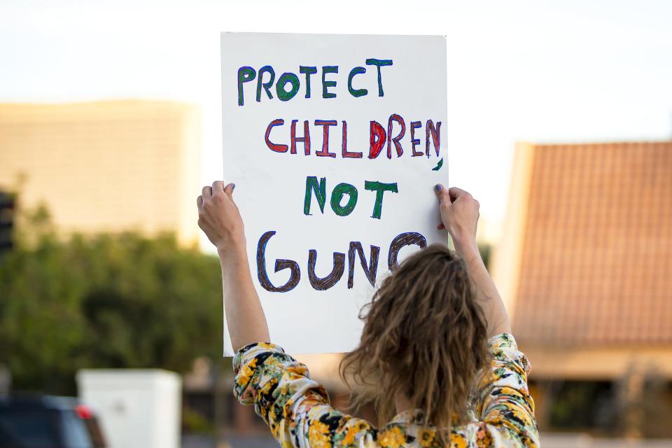 Austin Davis holds a sign that reads "Protect Children, Not Guns" during a demonstration against gun violence at the corner of Central Avenue and Roosevelt Street in Phoenix on May 28, 2022.