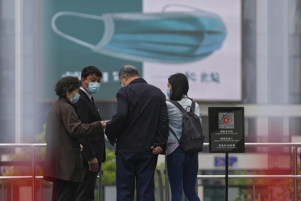 A security guard wearing a face mask stands watch as masked residents using their smartphone to scan their health code at a barricaded entrance to a commercial office complex, Sunday, April 24, 2022, in Beijing. Beijing is on alert after 10 middle school students tested positive for COVID-19, in what city officials said was an initial round of testing. (AP Photo/Andy Wong)