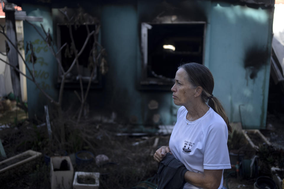 Irit Lahav poses in front of a neighbor's home that was destroyed by Hamas on Oct. 7 as they killed or captured a quarter of the residents of Kibbutz Nir Oz, near the Israel-Gaza border, Tuesday, Nov. 21, 2023. An Associated Press review of hundreds of messages shared among Nir Oz residents, security camera footage and Hamas instruction manuals show the group planned ahead of time to target civilians. (AP Photo/Maya Alleruzzo)