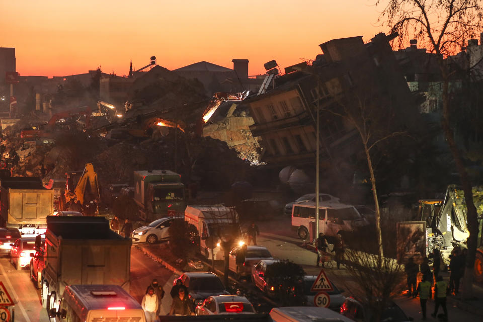 People walk among collapsed buildings, in Adiyaman, Friday, Feb. 10, 2023. Emergency crews made a series of dramatic rescues in Turkey on Friday, pulling several people, some almost unscathed, from the rubble, four days after a catastrophic earthquake killed more than 20,000. (AP Photo/Emrah Gurel)