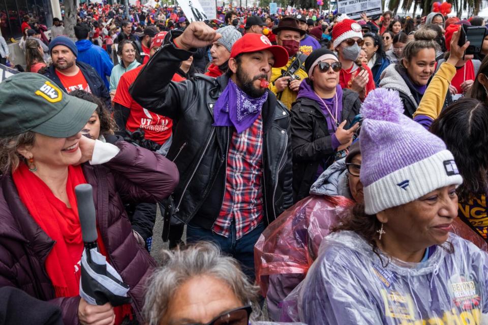 A man wearing a red cap raises a fist amid a crowd, some wearing red