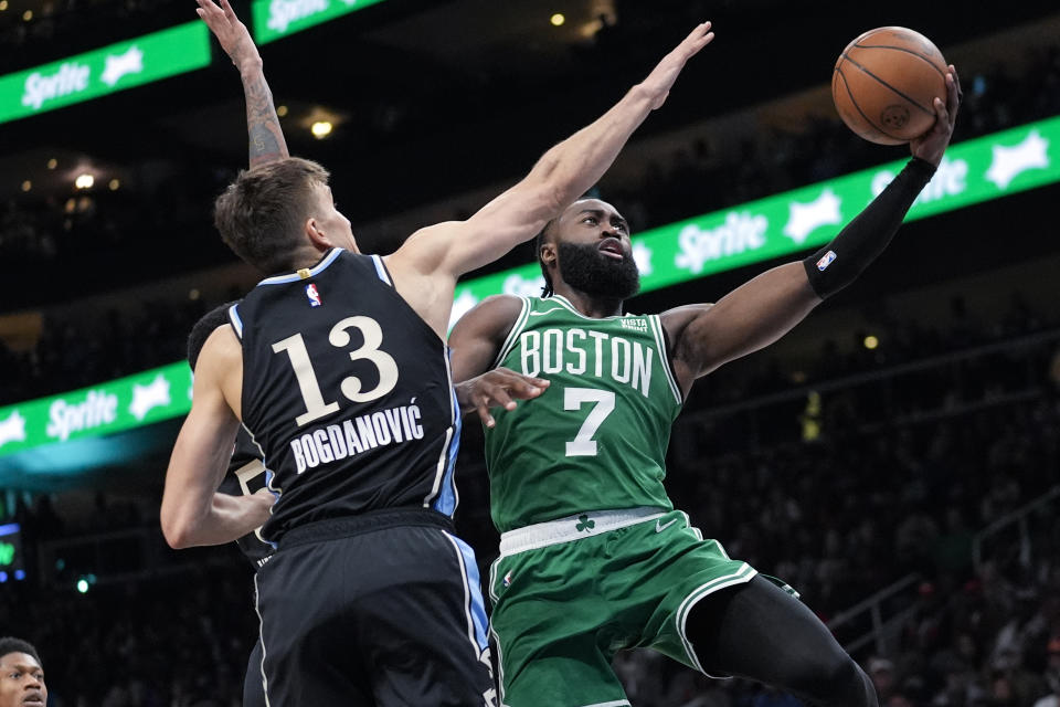 Boston Celtics guard Jaylen Brown (7) scores as Atlanta Hawks guard Bogdan Bogdanovic (13) defends during the second half of an NBA basketball game Monday, March 25, 2024, in Atlanta. (AP Photo/John Bazemore)