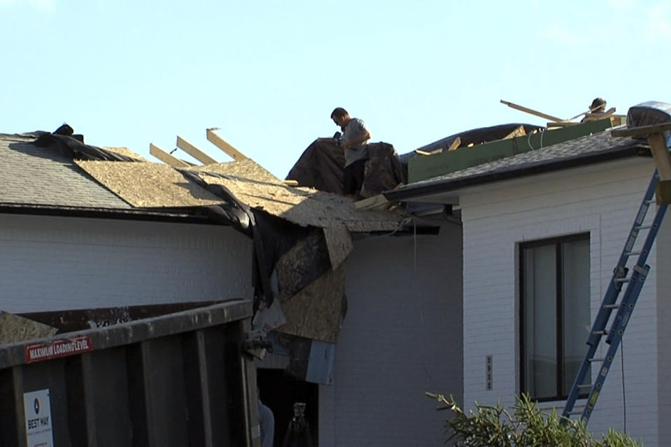 In this image taken from video, a man surveys a roof of a home severely damaged after a tornado touched down on Sunday, June 25, 2023, in Johnson County, Ind. Authorities said up to 75 homes were damaged. (WRTV via AP)