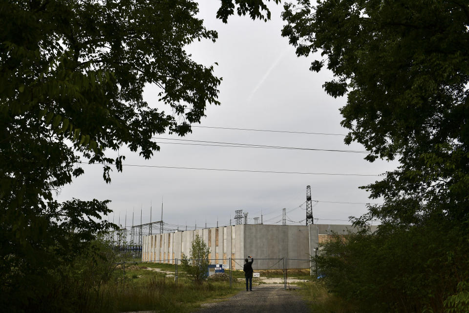 Independent lawmaker Akos Hadhazy, who has made a name for himself in Hungary as an anti-corruption crusader, snaps pictures at the site of a planned, but never finished government server farm to store the state's important data in God, Hungary, Wednesday, Sept. 14, 2022. The construction received nearly $40 million in EU funding in 2016, but was never finished, which Hadhazy says a clear sign of the missuse of EU funds. Hungarian prime minister Viktor Orban is facing a reckoning with the EU, which appears set to impose financial penalties on Hungary over corruption concerns and alleged rule-of-law violations that could cost Budapest billions and cripple its already ailing economy. (AP Photo/Anna Szilagyi)