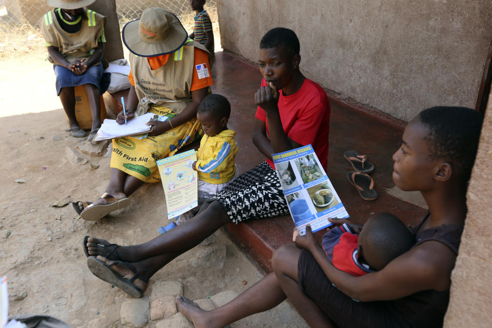 Community health worker, Rosemary Rambire, left, takes notes during a COVID-19 awareness campaign in Chitungwiza, on the outskirts of Harare, Wednesday, Sept. 23, 2020. As the Zimbabwe's coronavirus infections decline, strict lockdowns designed to curb the disease are being replaced by a return to relatively normal life. The threat has eased so much that many people see no need to be cautious, which has invited complacency. That worries some health experts. Rosemary Rambire says the improving figures and the start of the searing heat of the Southern Hemisphere’s summer could undermine efforts to beat back the virus even further. (AP Photo/Tsvangirayi Mukwazhi)