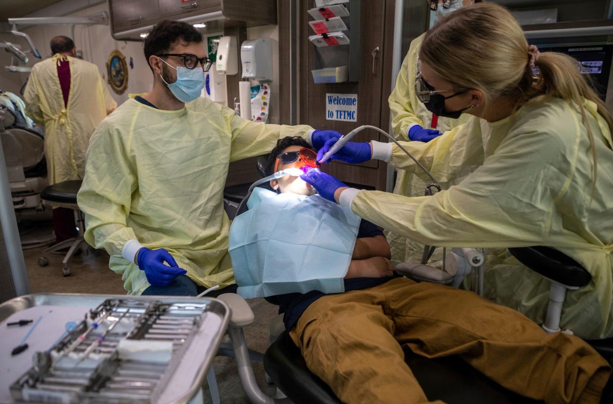 Khalil Dabaja, 25, and Grace Monette, 23, two third-year dental students at the University of Detroit Mercy School of Dentistry Dental Clinic, perform a fissure sealant on 9-year-old Philip Martinez-Rivera inside the Titans for Teeth Mobile Clinic at the Munger Elementary-Middle School in Detroit on April 26, 2023.