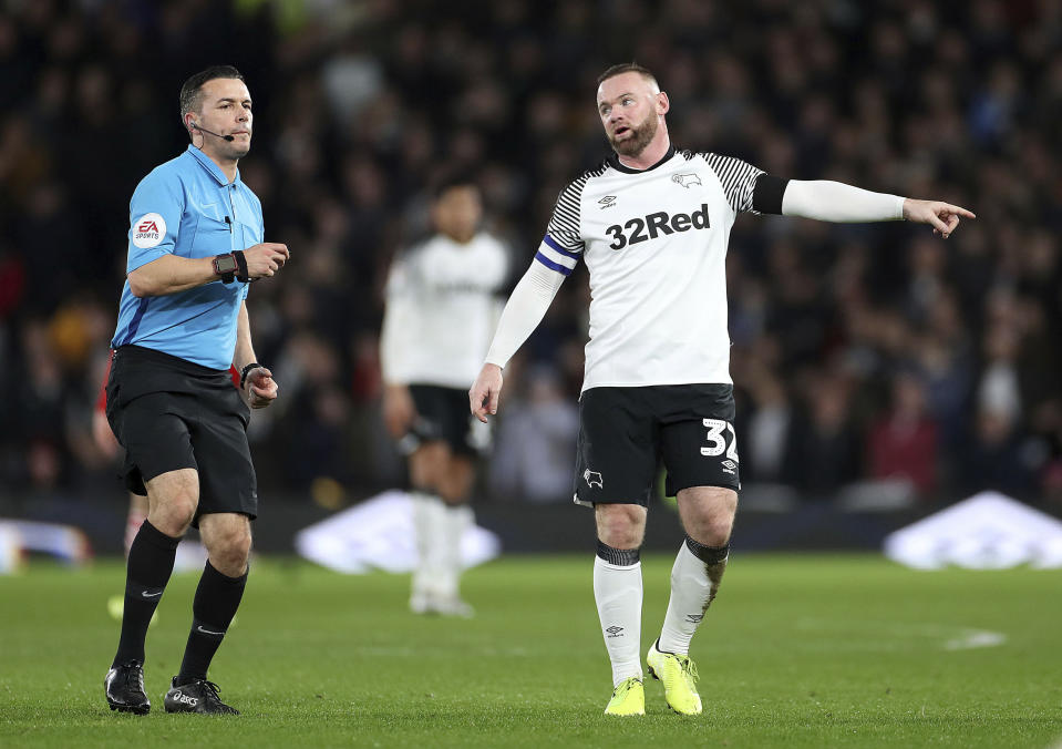 Derby County's Wayne Rooney talks with referee Dean Whitestone during the game against Barnsley, during their English Championship soccer match at Pride Park in Derby, England, Thursday Jan. 2, 2020. (Bradley Collyer/PA via AP)