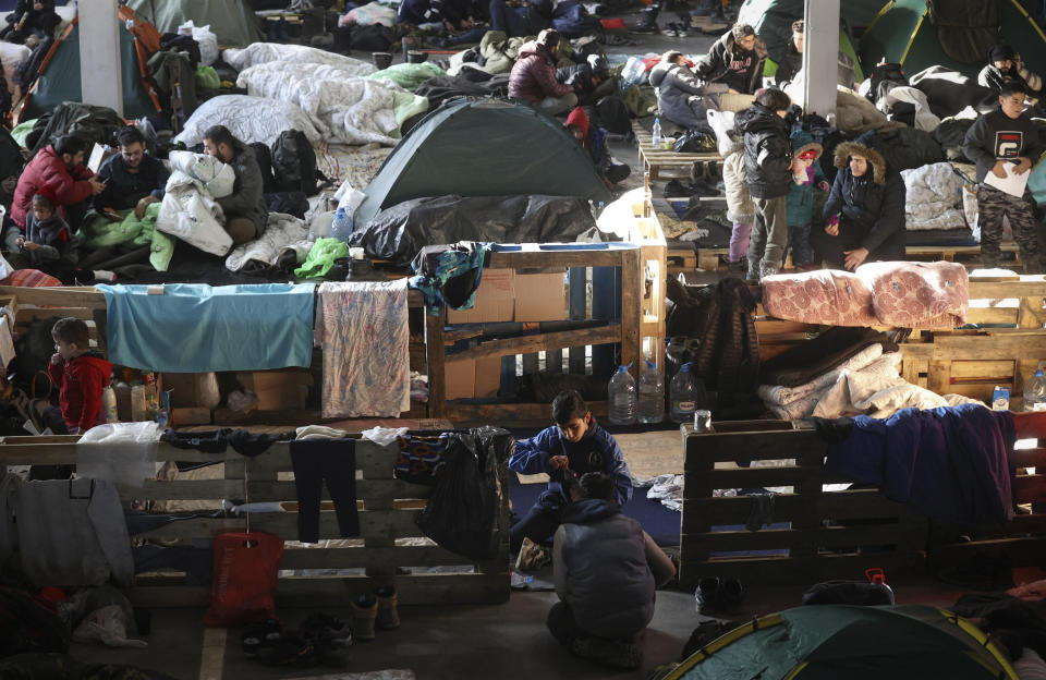 Migrants settle in the logistics center of the checkpoint "Bruzgi" at the Belarus-Poland border near Grodno, Belarus, Wednesday, Dec. 1, 2021. The West has accused Belarusian President Alexander Lukashenko of luring thousands of migrants to Belarus with the promise of help to get to Western Europe to use them as pawns to destabilize the 27-nation European Union in retaliation for its sanctions on his authoritarian government. Belarus denies engineering the crisis. (Oksana Manchuk/BelTA via AP)