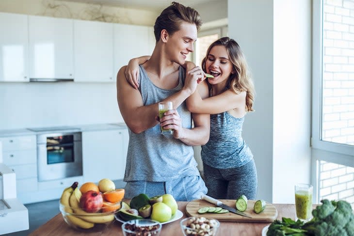 Man and woman snacking on healthy food in kitchen