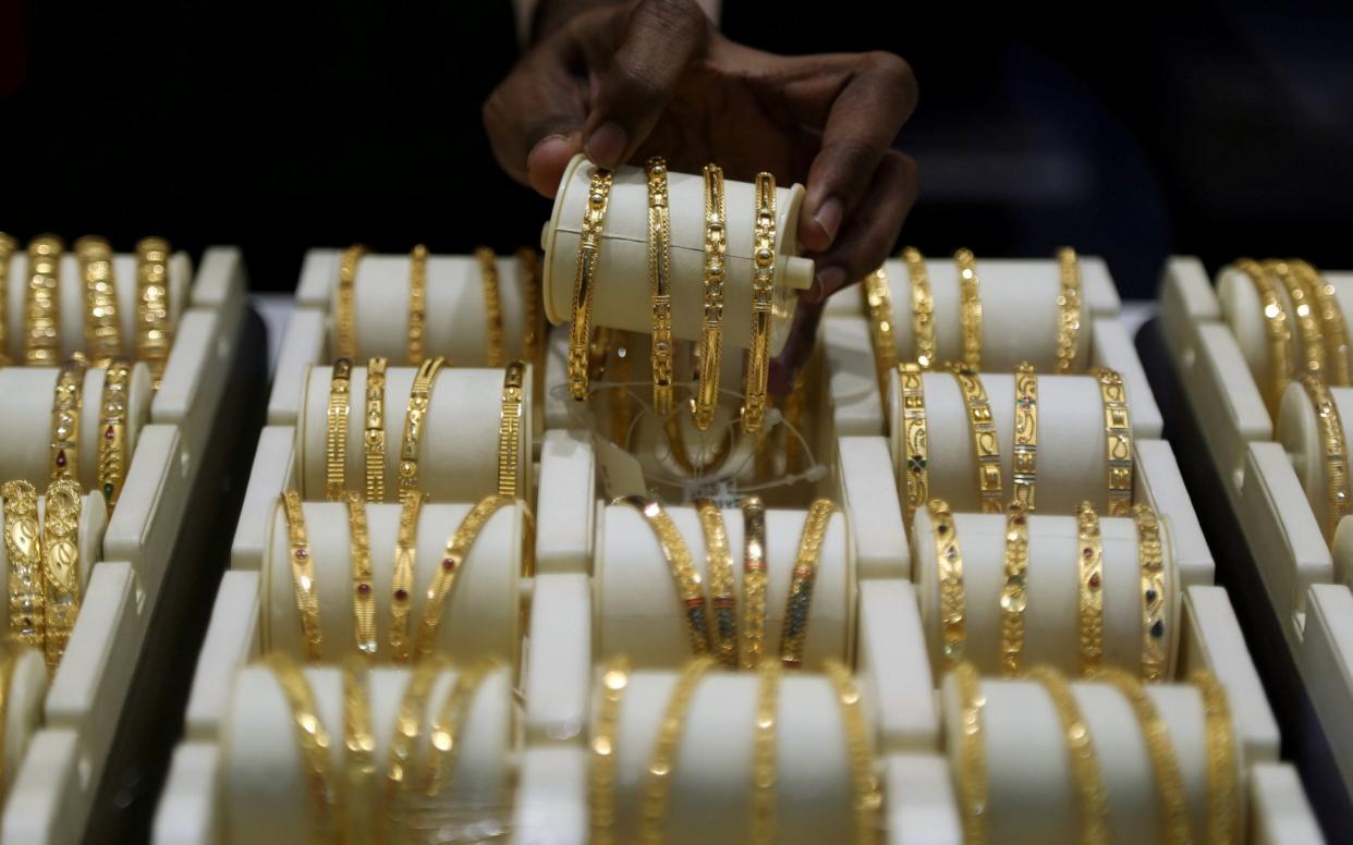 A salesman arranges gold bangles inside a jewellery showroom