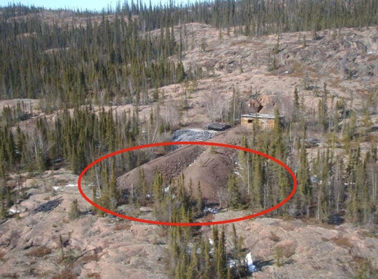 A photo taken in 2009 gives an aerial view of waste rock piles, circled in red, and the mine's partially concealed entrance.  