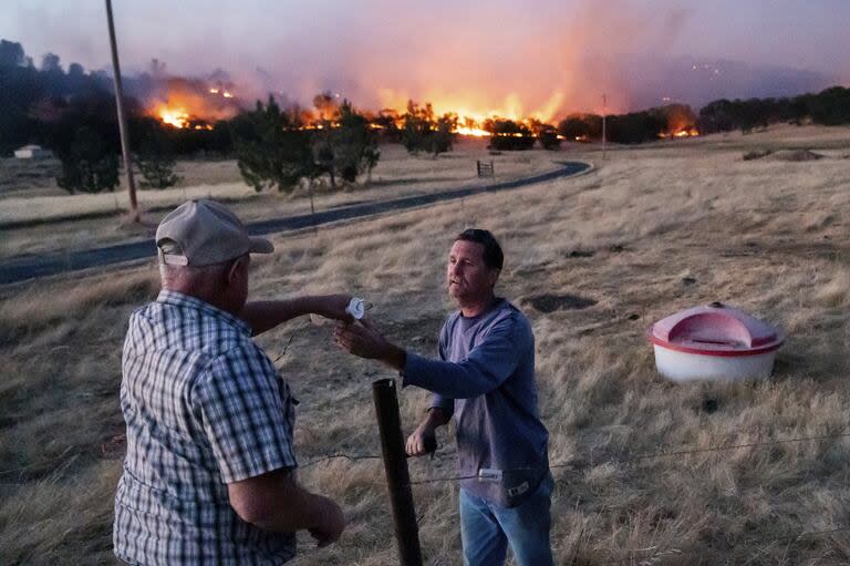 Un ganadero vuelve a conectar una valla después de atender al ganado mientras arde el Aero Fire en la comunidad de Copperopolis del condado de Calaveras, California.
