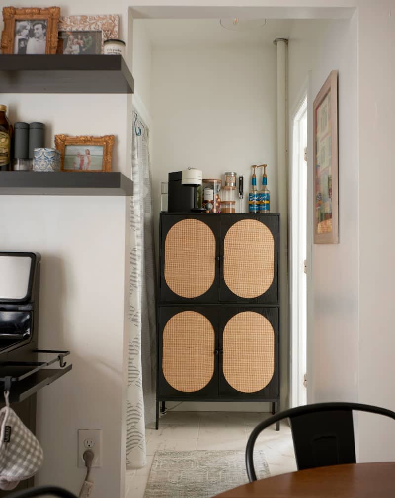 Coffee maker and ingredients on wood and rattan cabinet in nook off of kitchen.