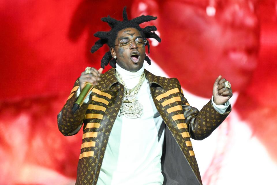 Kodak Black wearing glasses and holding a mic on stage