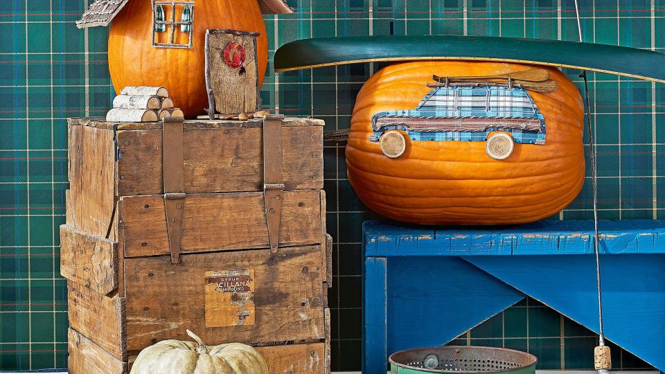 cabin, wagoneer, fishing bobs pumpkin display pictured with wood crates, rustic blue bench, fishing rod, green plaid wallpaper