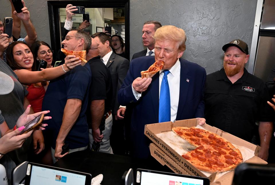 Former President Donald Trump eats a slice of pizza at Downtown House of Pizza after speaking at the Lee County Republican dinner in Fort Myers Friday.