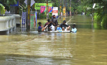 People move past a flooded area in Thrissur, in the southern Indian state of Kerala, Friday, Aug. 17, 2018. Rescuers used helicopters and boats on Friday to evacuate thousands of people stranded on their rooftops following unprecedented flooding in the southern Indian state of Kerala that left more than 100 dead. (AP Photo)