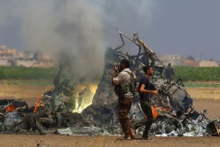 Men inspect the wreckage of a Russian helicopter that had been shot down in the north of Syria's rebel-held Idlib province, Syria August 1, 2016. REUTERS/Ammar Abdullah