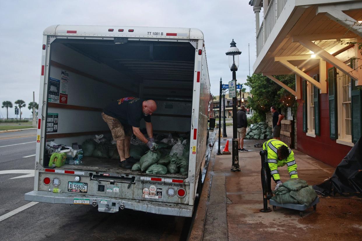 Chris Tyler, left, kitchen manager at Harry's Seafood Bar & Grille and Ordjoul Shivers, a cook at the same restaurant, helps to remove sandbags Friday, Sept. 30, 2022 in St. Augustine. Hurricane Ian, that was later reduced to a tropical storm, ripped through the region Thursday bringing winds, rain, flooded roads, power outages and downed trees. [Corey Perrine/Florida Times-Union]