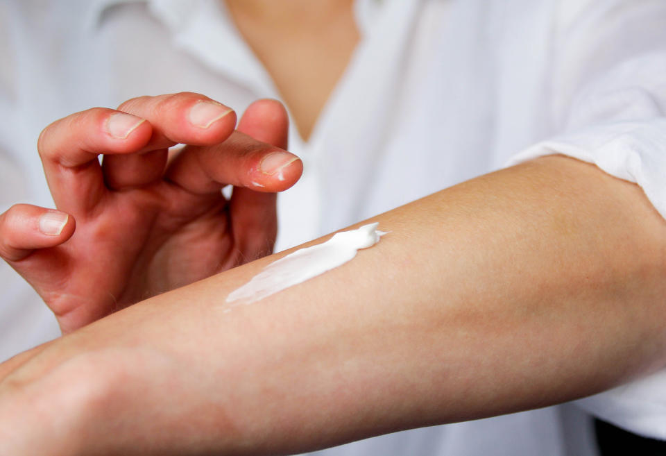 A person is rubbing sunscreen on their arm