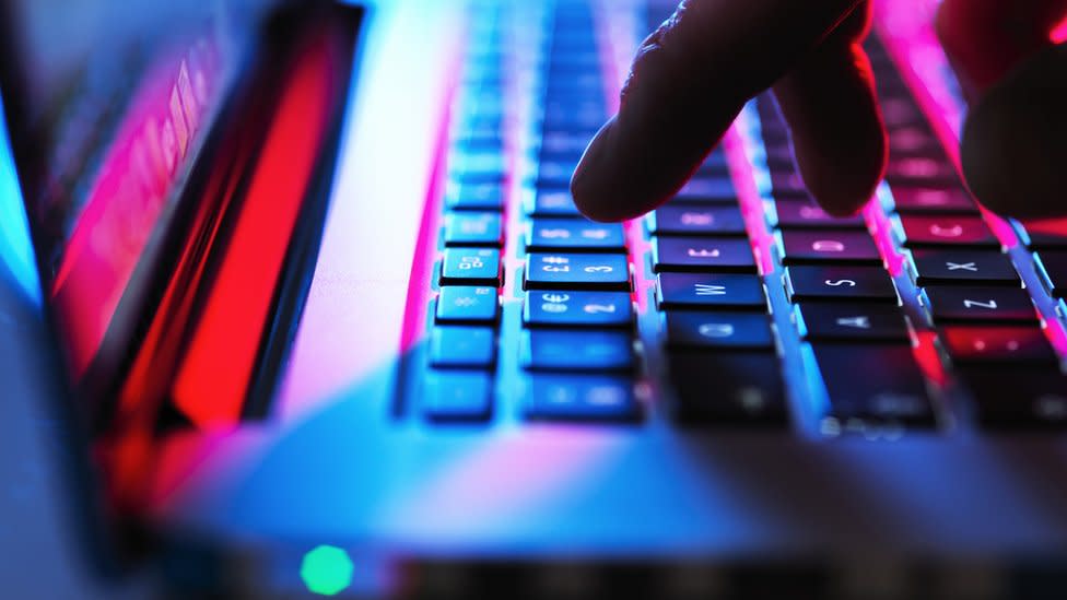 A man's hand seen typing on a laptop keyboard