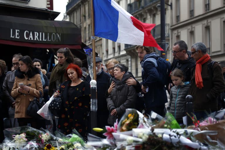 En esta imagen del 16 de noviembre de 2015, personas se reúnen frente a la cafetería Le Carillon, lugar de los atentados terroristas, en París. (AP Foto/Jerome Delay)