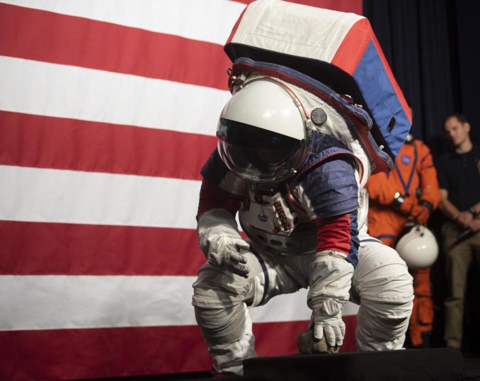 Kristine Davis squats to pick up a rock to show the flexibility of the exploration extravehicular mobility unit.