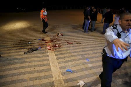 An Israeli policeman clear the spot where, according to Israeli police spoksperson, at least 10 Israelis were stabbed, in the popular Jaffa port area of Tel Aviv, Israel March 8, 2016. REUTERS/Amir Cohen