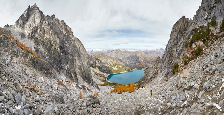 Hiker climbing Aasgard Pass with alpine lakes and surrounding mountains on The Enchantments