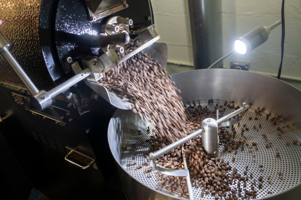 Freshly roasted beans pour out of the roaster at Alla Prima roastery on Thursday, May 25, 2023