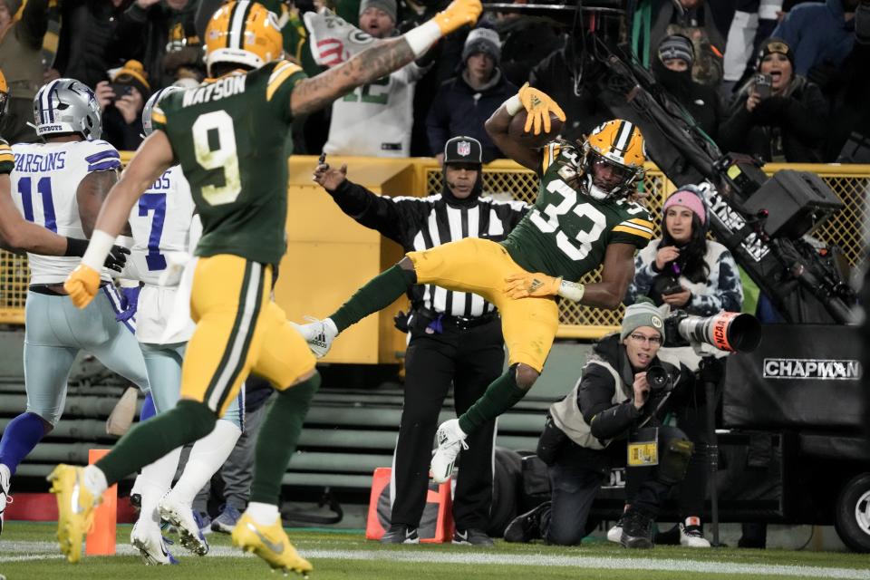 Green Bay Packers running back Aaron Jones (33) dives into the end zone to score a touchdown as wide receiver Christian Watson (9) celebrates during the first half of an NFL football game against the Dallas Cowboys Sunday, Nov. 13, 2022, in Green Bay, Wis. (AP Photo/Morry Gash)