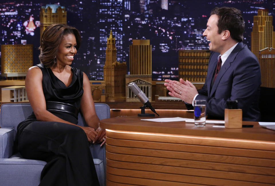 FILE- In this Feb. 20, 2014 photo provided by NBC, host Jimmy Fallon applauds first lady Michelle Obama on the set of “The Tonight Show Starring Jimmy Fallon,” in New York. Aside from Fallon wanting to do the show in New York City, NBC could have viewed a 30 percent tax break as incentive to bring the show back from the West Coast after 40 years. The tax credit, designed to lure certain types of programming to New York, can potentially save the network $20 million dollars a year. (AP Photo/NBC, Lloyd Bishop, File)
