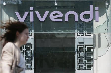 A woman walks walk past the main entrance of the entertainment-to-telecoms conglomerate Vivendi's headquarters in Paris April 8, 2015. REUTERS/Gonzalo Fuentes