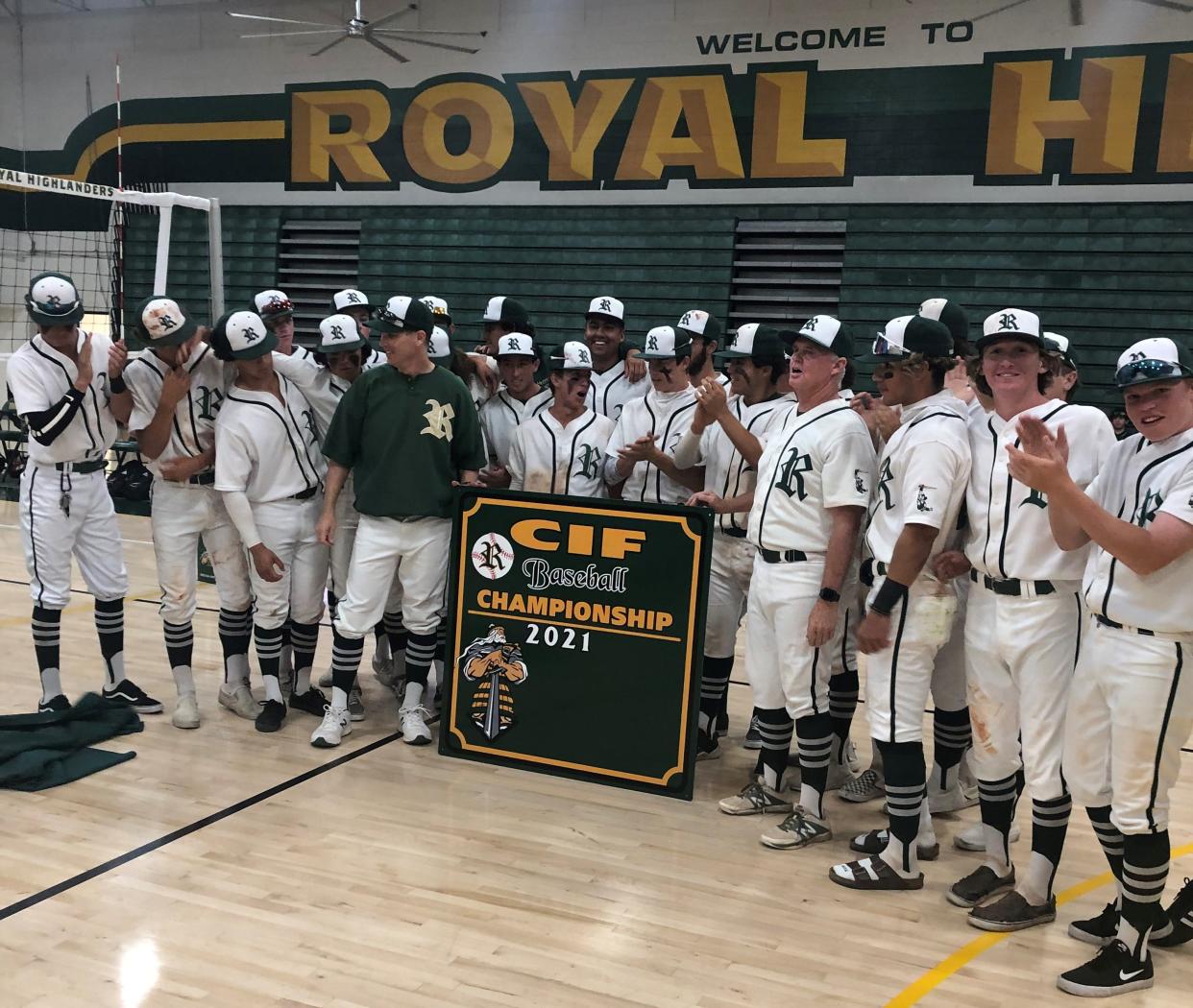 The Royal High baseball team poses with its CIF-SS championship banner from the 2021 season on Thursday at the school gym. The Highlanders clinched a share of the Coastal Canyon League title by beating Simi Valley earlier in the day.