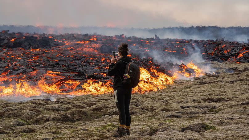 A person walks near lava emerging from a fissure of the Fagradalsfjall volcano near Litli-Hrútur Mountain, July 10, 2023.