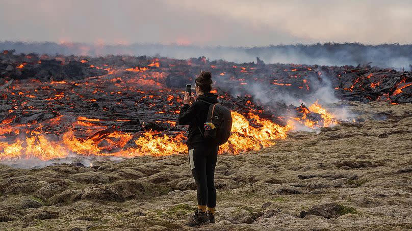 A person walks next to lava coming out of a fissure of the Fagradalsfjall volcano near the Litli-Hrútur mountain, 10 July 2023.