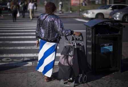 A woman pauses to smoke a cigarette as she stands on a sidewalk along West 125th street in New York City, August 2, 2013. REUTERS/Mike Segar