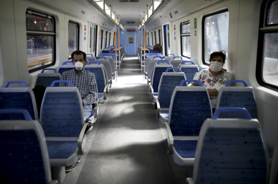 Pasajeros usan máscaras como precaución contra la propagación del nuevo coronavirus en un tren vacío en Buenos Aires, Argentina, el viernes 20 de marzo de 2020. (AP Foto / Natacha Pisarenko)