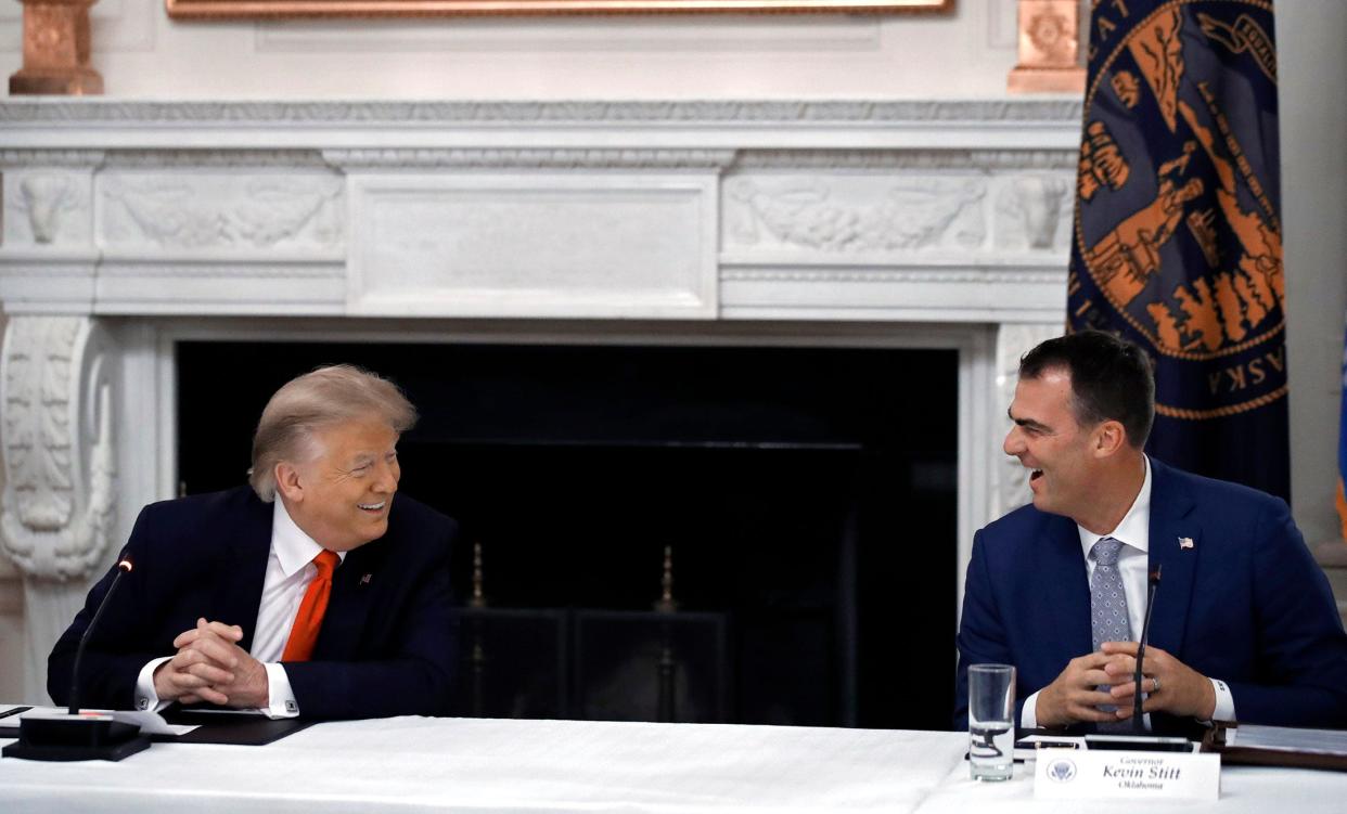 President Donald Trump laughs with Oklahoma Gov. Kevin Stitt during a roundtable with governors on the reopening of America's small businesses, in the State Dining Room of the White House, Thursday, June 18, 2020, in Washington. (AP Photo/Alex Brandon)