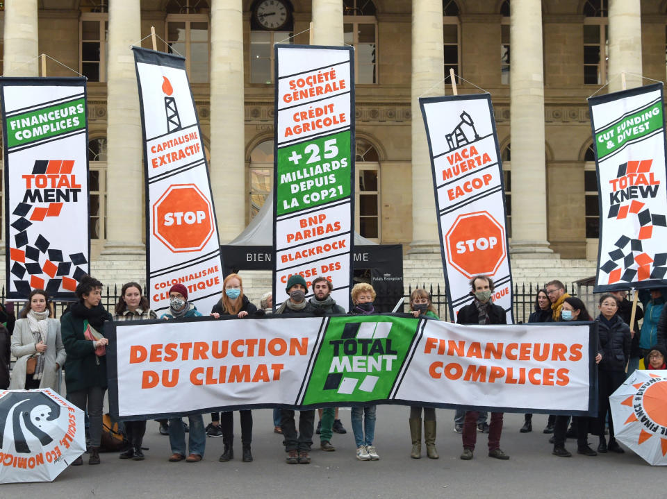 ‘350.org’ activists hold a banner reading ‘Destruction of the climate - Total lies - complicit finance’ at the former Paris stock exchange Palais Brongniart in Paris on Friday, during a protest against French energy company Total. (AFP via Getty Images)