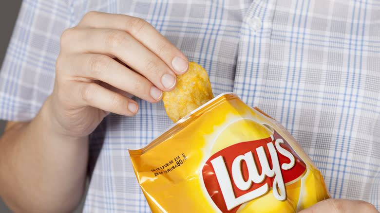 Hand holding bag of Lay's potato chips