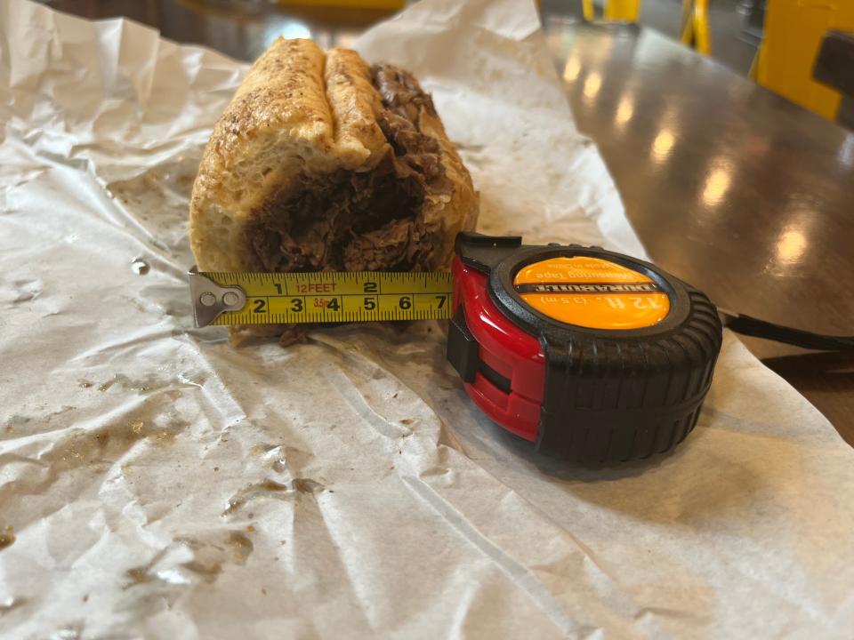 A tape measure measuring the width of a sandwich.