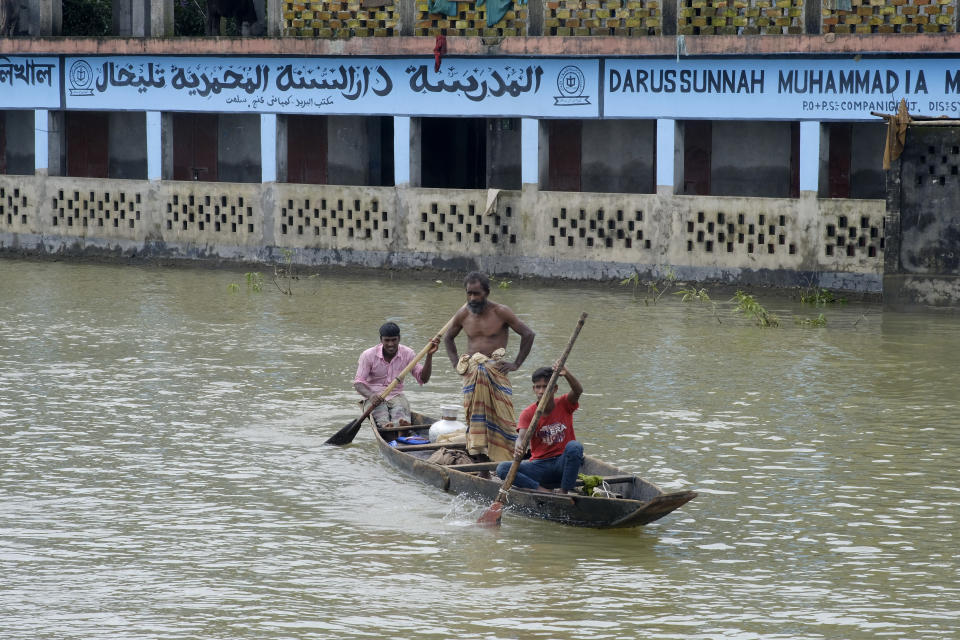 Flood affected people row a country boat as they head to collect their belongings from a walkway in Sylhet, Bangladesh, Wednesday, June 22, 2022. (AP Photo/Mahmud Hossain Opu)
