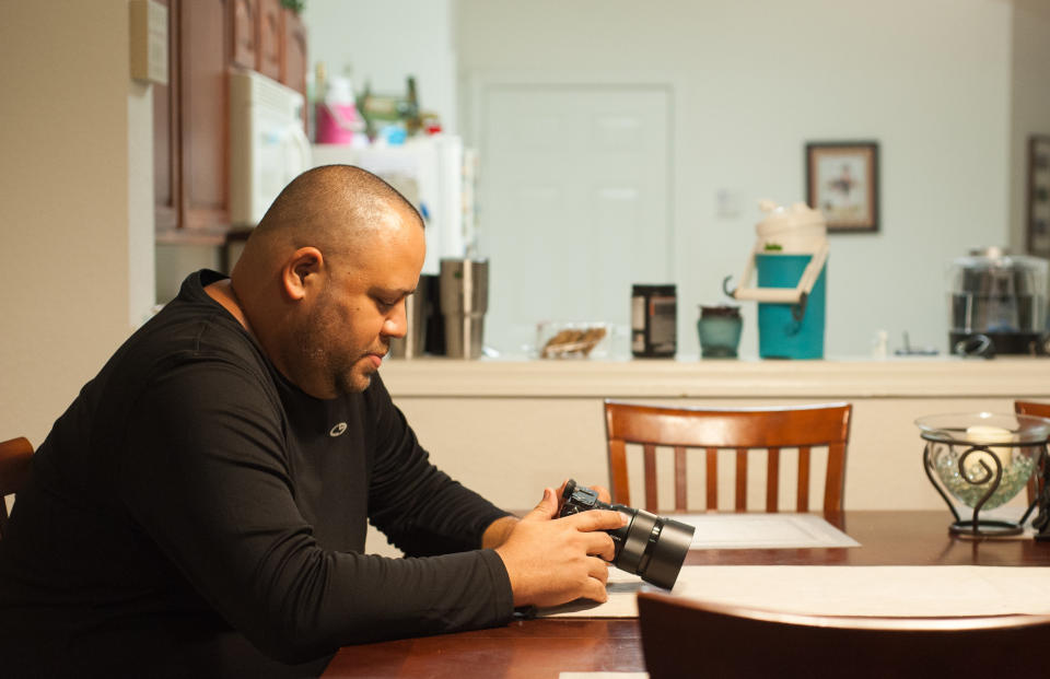 Delgado, in his home, looks at his camera. He took up photography after the Pulse shooting as a way to cope with his PTSD. (Photo: Chris McGonigal/HuffPost)