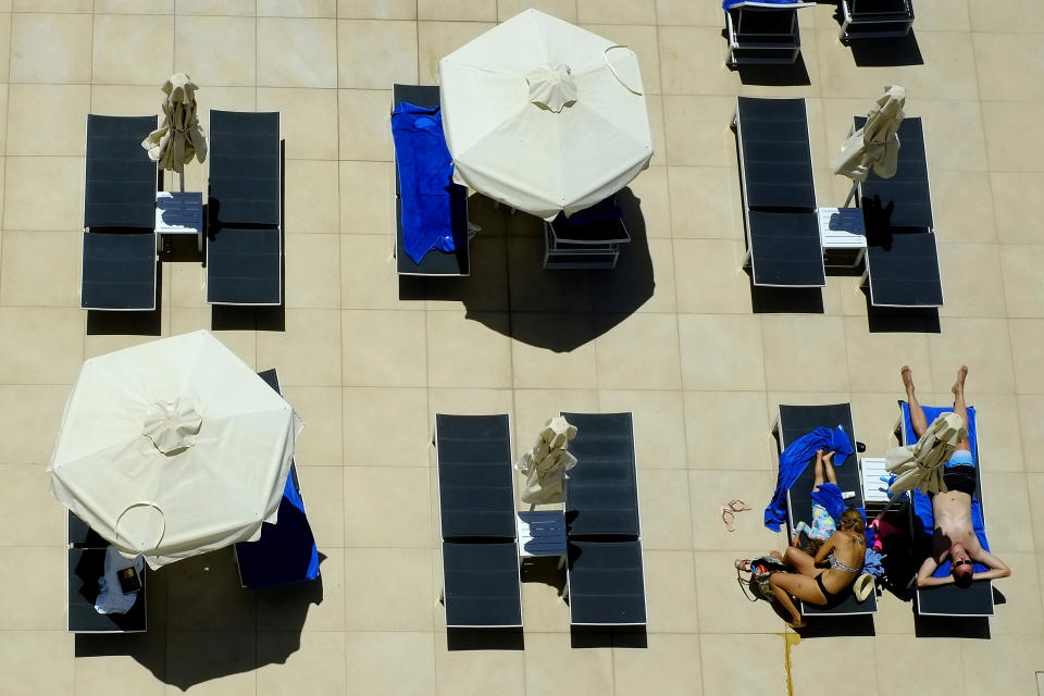 FILE - In this May 22, 2021, file photo, a family on vacations lounges at the pool of Nissi Blue hotel in southeast resort of Ayia Napa, in the eastern Mediterranean island of Cyprus. Coronavirus infections, hospitalizations and deaths are plummeting across much of Europe. Italy and Cyprus are due to let restaurants reopen for indoor dining June 1, with discos — a big summertime moneymaker for southern European beach resorts — scheduled soon thereafter. (AP Photo/Petros Karadjias)