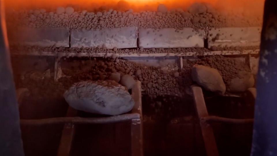 Balls of clay inside a furnace with glowing red flames in the background.