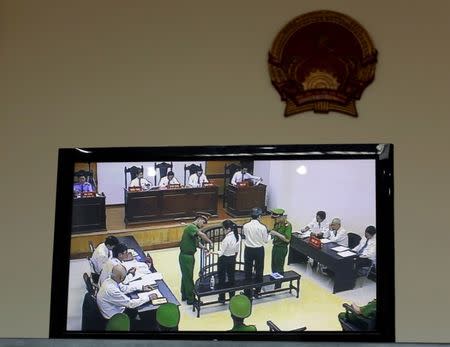 A live screen from the courtroom reserved for media and diplomats shows policemen removing the handcuffs of Vietnamese prominent blogger Anh Ba Sam, whose real name is Nguyen Huu Vinh (center R), and his assistant Nguyen Thi Minh Thuy (center L) during their appeal trial in Hanoi, Vietnam September 22, 2016. REUTERS/Kham